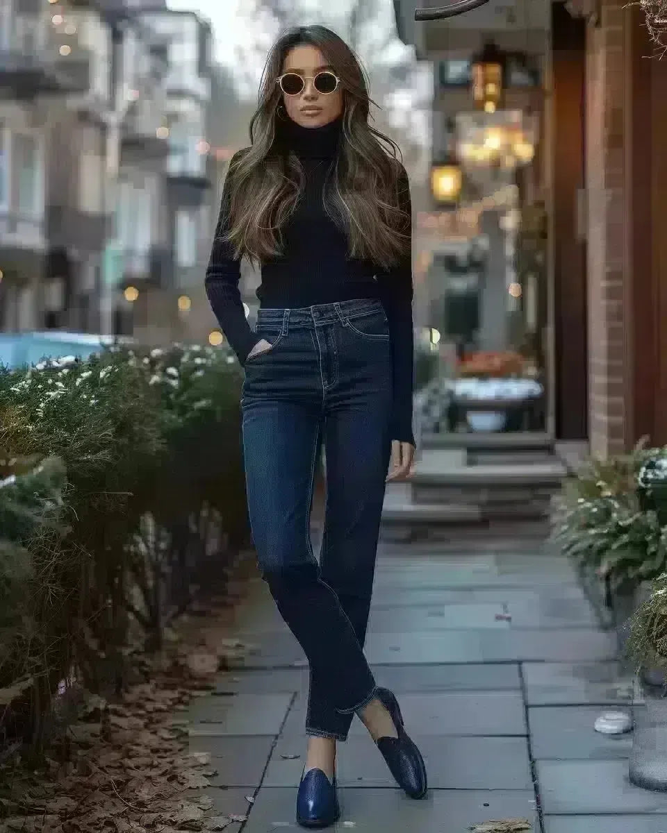 Elegant woman in dark-wash high-waisted jeans and blue loafers outdoors. Late Winter  season.