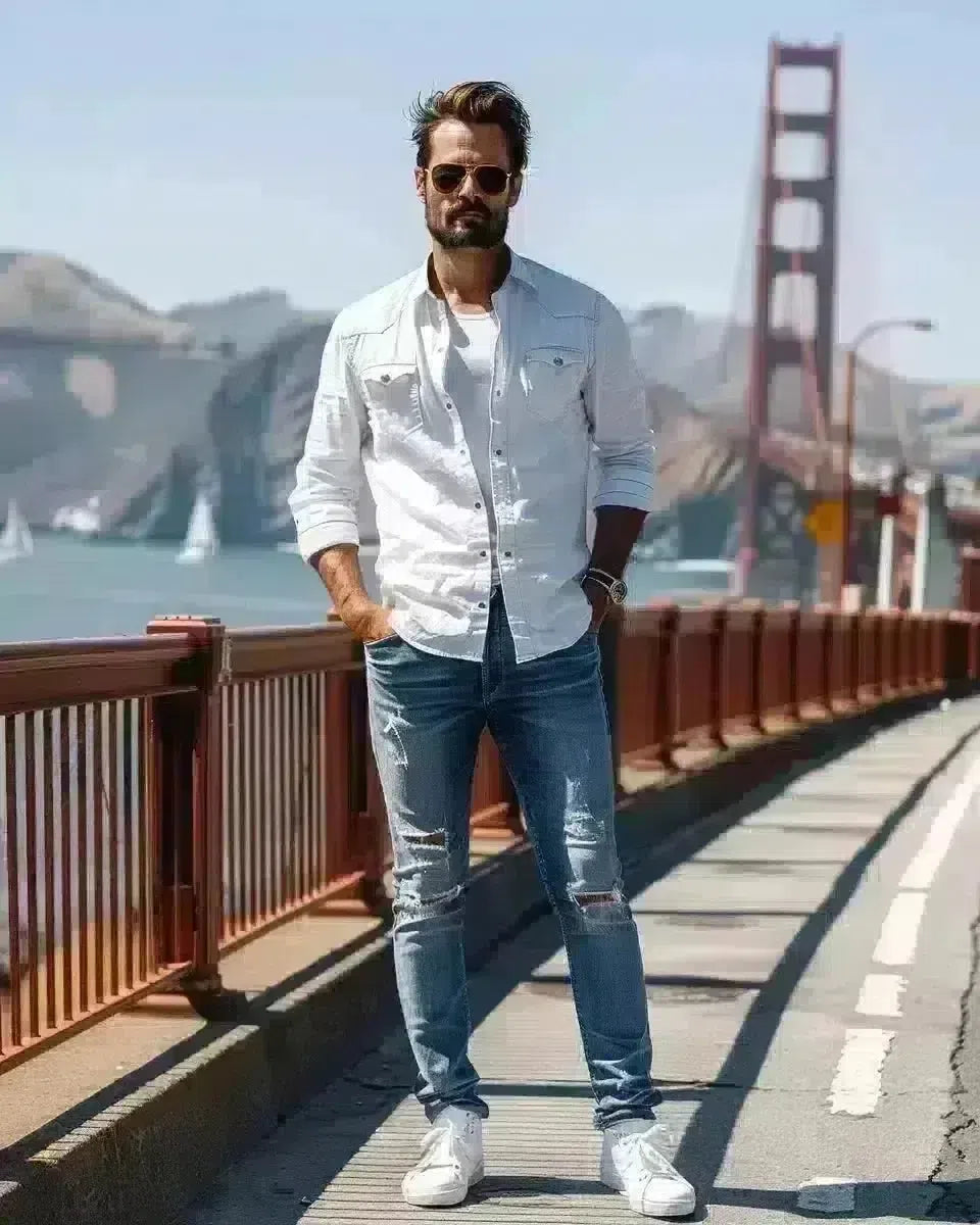 Confident man in blue ripped jeans, white shirt at Golden Gate Bridge. Spring season.