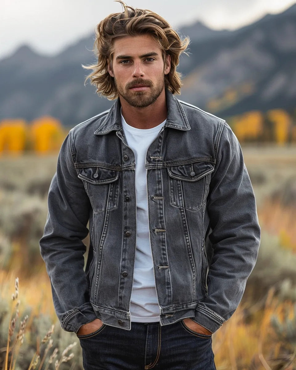 A man models a stylish grey denim jacket, paired with a white t-shirt and dark blue jeans. Rugged yet fashionable. Autumn season. Australian male. Yellowstone National Park, Yellowstone, WY background.