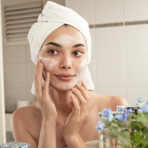 A woman applying face cream as part of her skincare routine, symbolizing the importance of daily care for smooth, wrinkle-free skin.