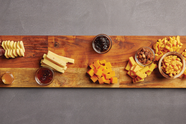 Image of cheeses added to wooden board around jars