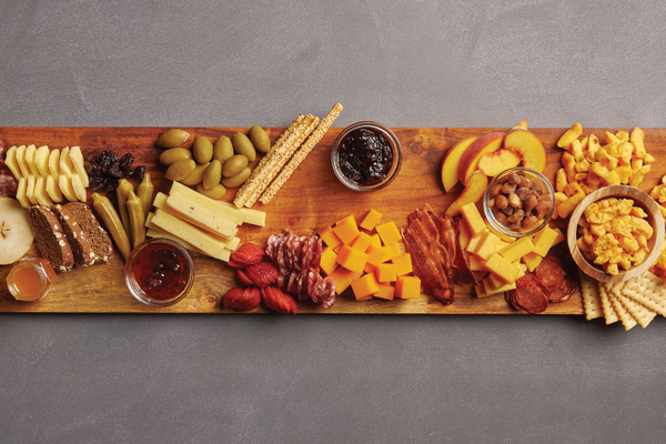 Image of fruits and vegetables being added to cheese board