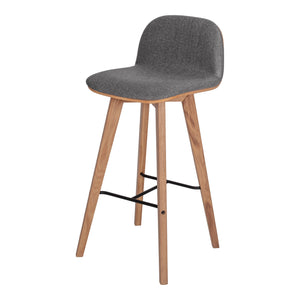 Bar Stool. This piece of dining room furniture features a low backrest and solid Oak legs. Grey Upholstery. Angle View.