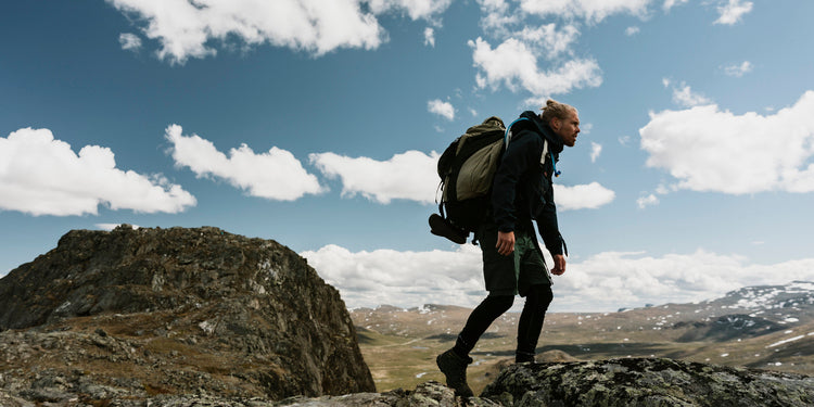 Mann mit veganer Kleidung in den Bergen am Wandern.