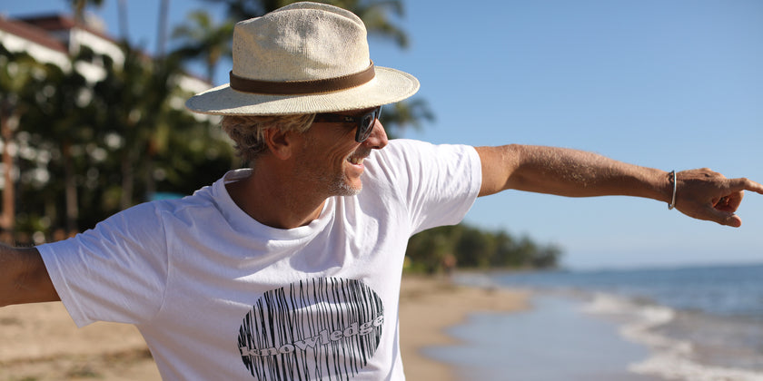 Mann mit veganem T-Shirt am Strand.