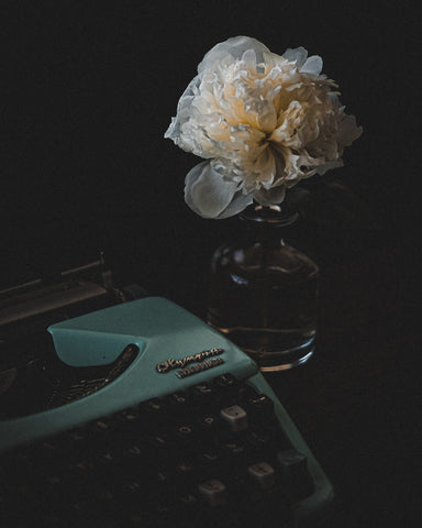 An intimate setting of a vintage typewriter with a peonie