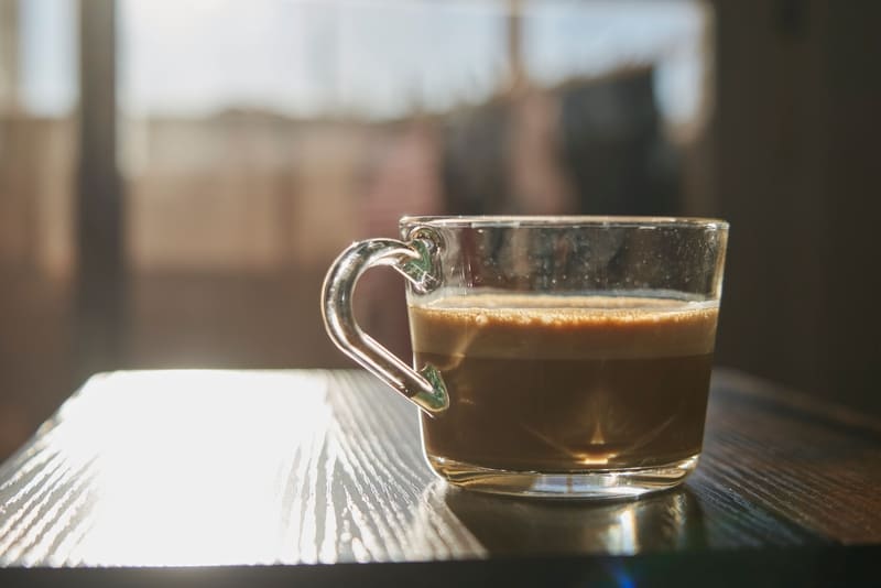 dolce-gusto-cup-of-foamy-latte-coffee-next-to-backlight-on-wooden-table