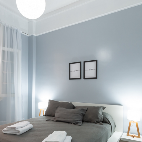 Chambre à coucher avec draps marrons et mur bleu pastel.