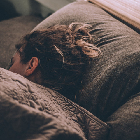 femme qui dort sur le côté dans des dras marrons.