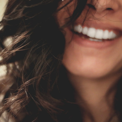 Femme brune qui sourit avec des dents blanches.