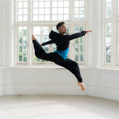 Dancer Kevin Tristan in our Rise Cropped Hoodie and Freedom Harem Joggers in a dance jump in mid air