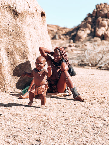 Himba Dorf Frau mit Kind vor einer Hütte