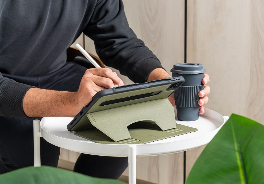 Person using a stylus on a tablet with a stand, next to a reusable coffee cup