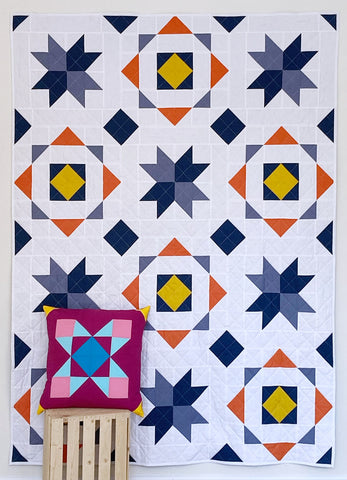 Block adventures quilt pattern by Monika Henry and Katy Devlin - large throw size quilt in blues with yellow and orange accents, and a pillow in pink and blue
