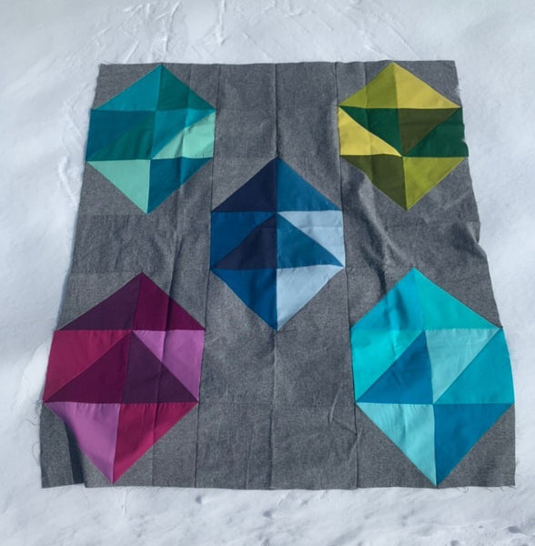 Facets modern gemstone quilt pattern by Monika Henry of Penny Spool Quilts - Quilt featuring modern, simplified gemstones in a variety of colours on grey background