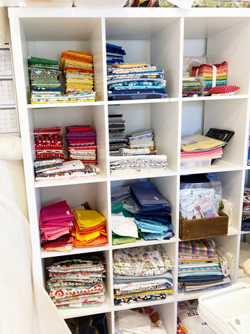 cubby shelf with fabrics folded and sorted by colour