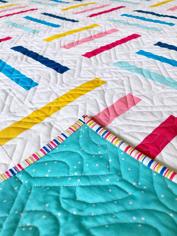 Bar Code Quilt pattern by Penny Spool Quilts - throw quilt in multicoloured stripes on white background, with turquoise backing