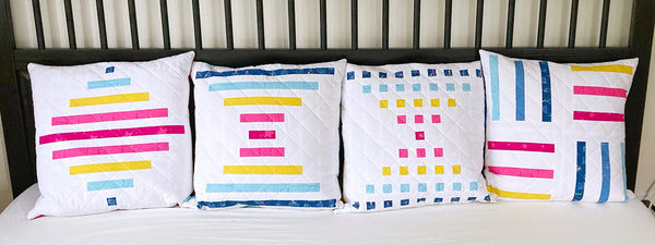 Bar quilt pattern collection by Penny spool quilts - pillows in multicolour on white, on a bed