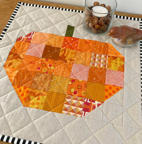Scrappy Apple quilt block pattern by Penny Spool Quilts - quilted table topper featuring scrappy orange pumpkin on linen background