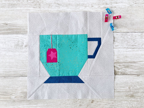 Teacup FPP Quilt Block Pattern by Penny Spool Quilts - turquoise teacup with pink teabag tag and navy handles, on grey background