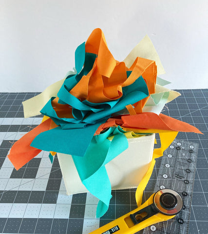 basket overflowing with fabric scraps in orange and turquoise