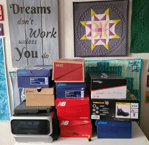 stack of shoe boxes in front of a quilted wall hanging