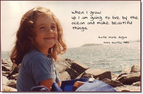 kate shepherd as a little girl sitting by the ocean smiling