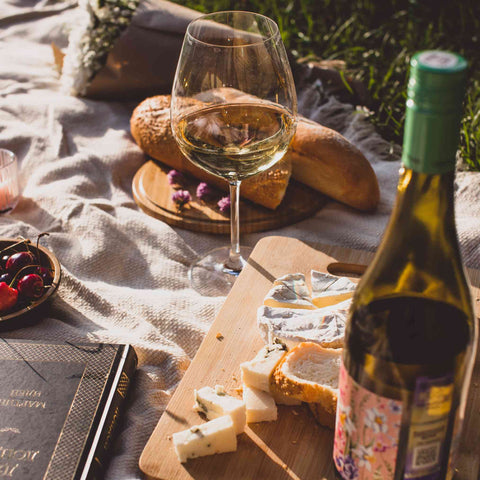 Outdoor wine picnic with white wine, French bread, picnic blanket and carvery.