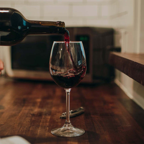 Red wine on a wooden table, a man pouring red wine