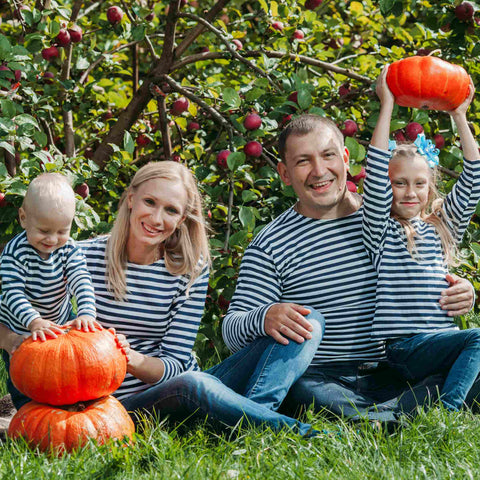 A happy family gathering on the grass with pumpkins in hand