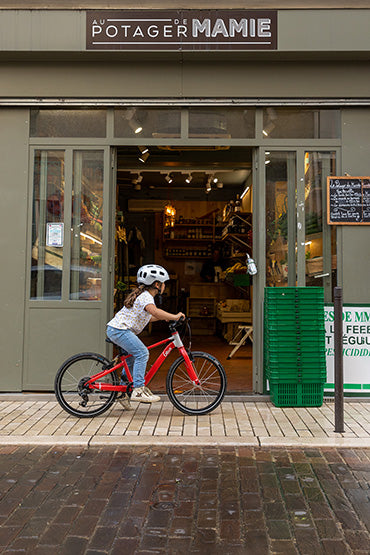 Enfant passe devant le primeur en vélo 20 pouces Gibus Cycles