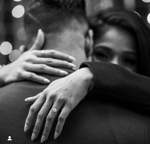 A woman with her hand on her husband's neck, showcasing her diamond engagement ring