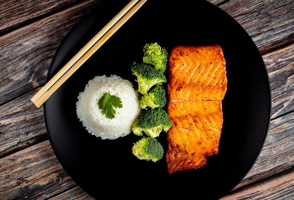 A plate of rice with salmon and broccoli.