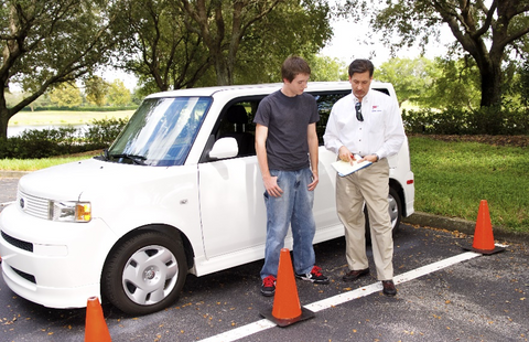Student and instructor going over checklist standing by a car