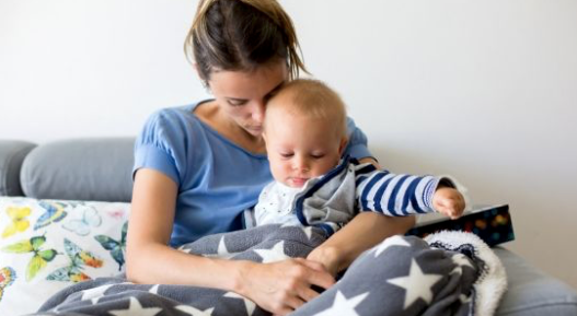 mom sitting with baby on the bed