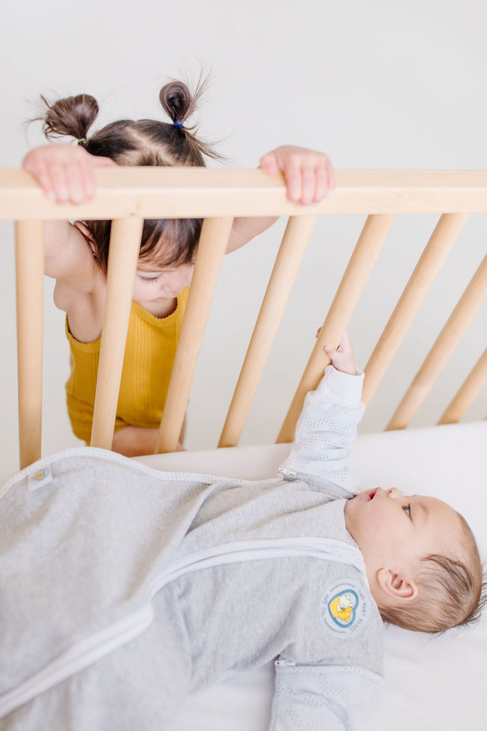 baby in crib with sister watching