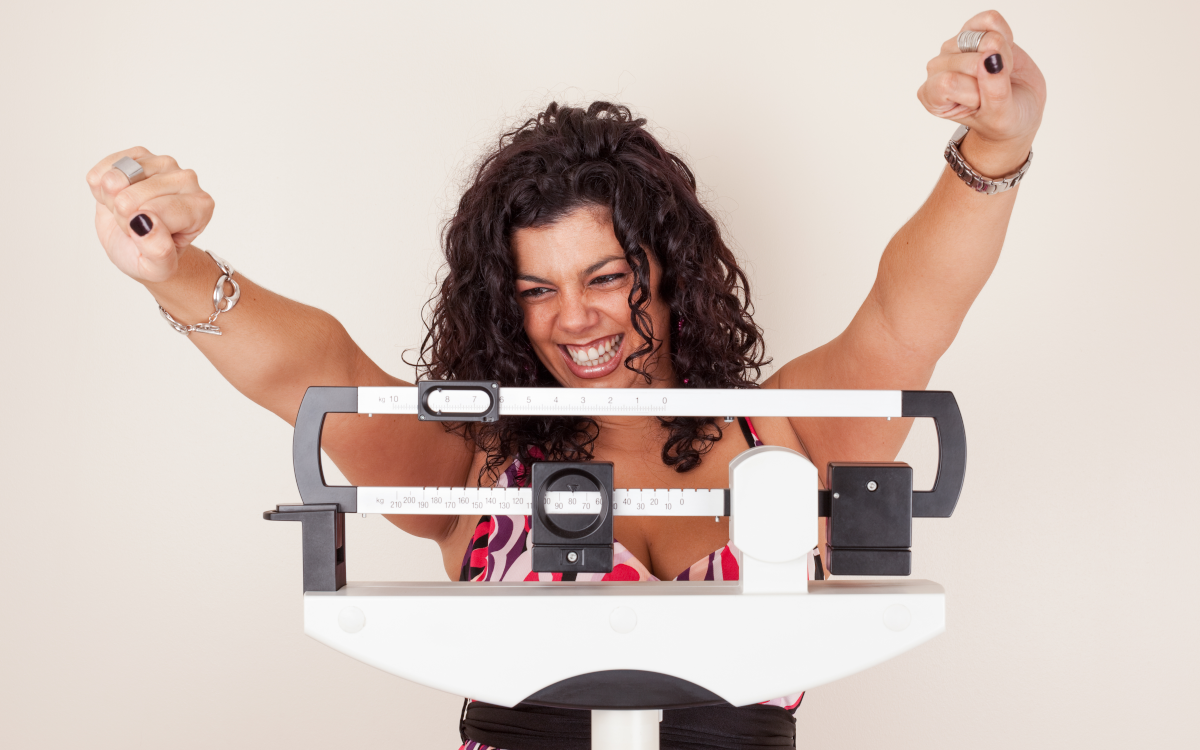 woman celebrating while on weighing scales