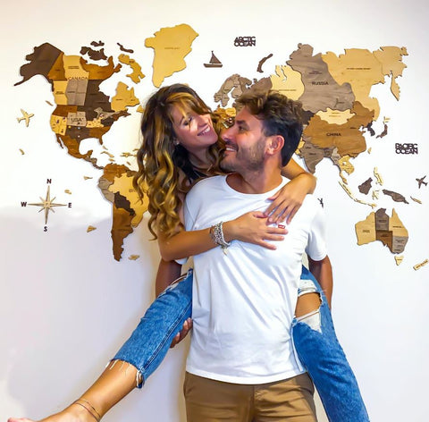 Pareja frente a su mapa mundial de madera en 3D