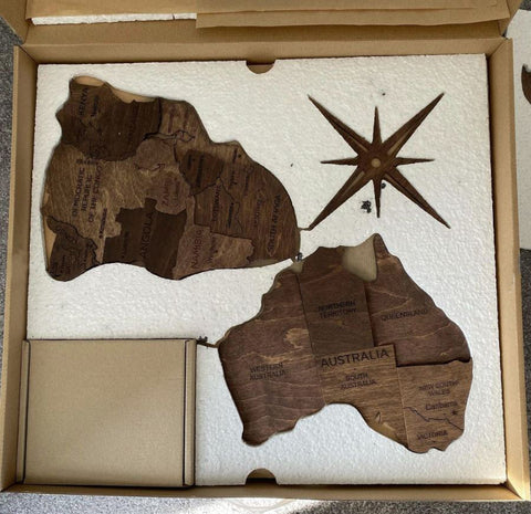 The pieces of a 3D Wooden World Map in Oak Color in the box