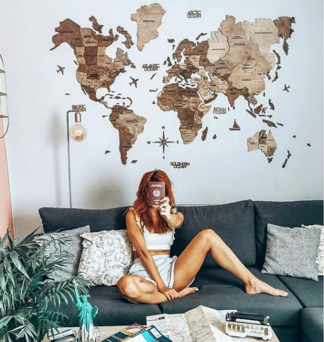 3D Weltkarte Holz in Terra-Farbe mit einer Frau, die ihren Reisepass zeigt
