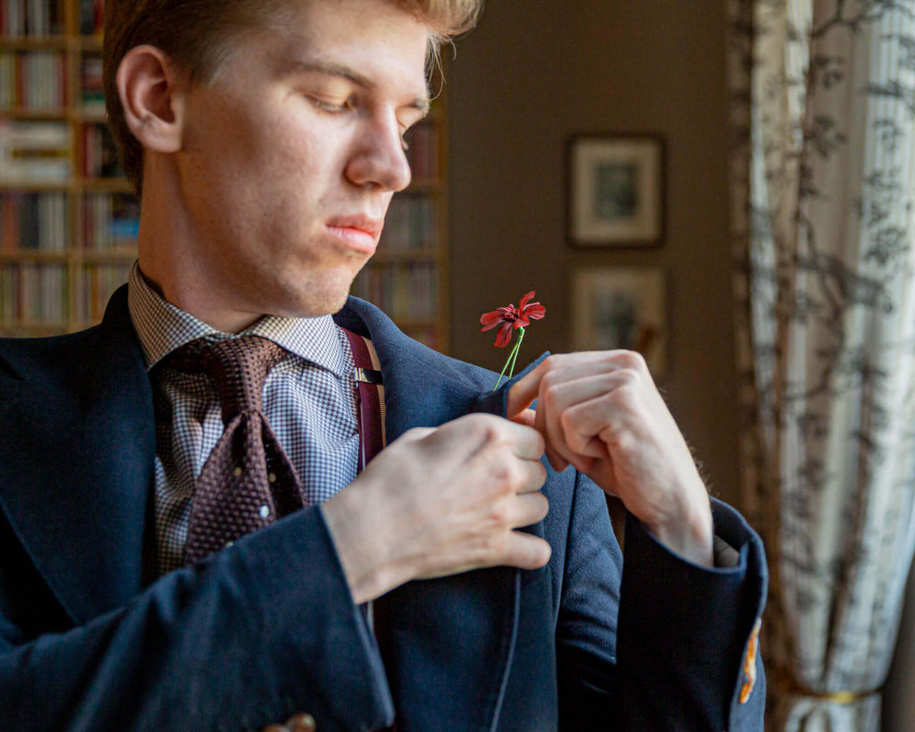 Joost Bom mit blauem Jackett, brauner Krawatte aus Seidentrick von Carlo Fumeo und einer seidenen Boutonnière (Knopflochblume)