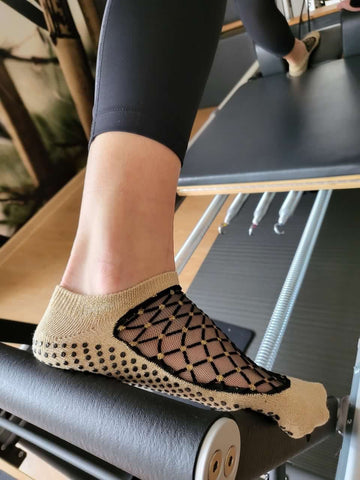 Grip-Socken mit glitzerndem Netz am oberen Teil der Füße in Schwarz und Gold der Marke Shashi