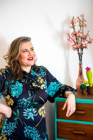 Image of Corinne looking to the right in a turquoise and dark blue dress