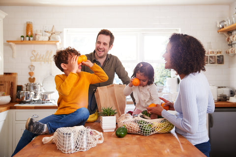 Family happily putting groceries away using plastic-free shopping bags