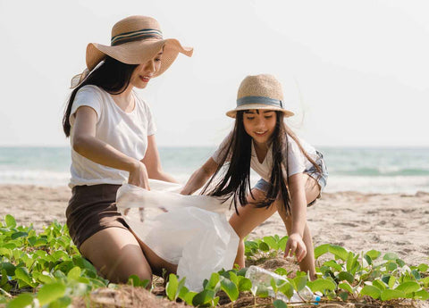 mother and daughter cleaning up rubbish from beach