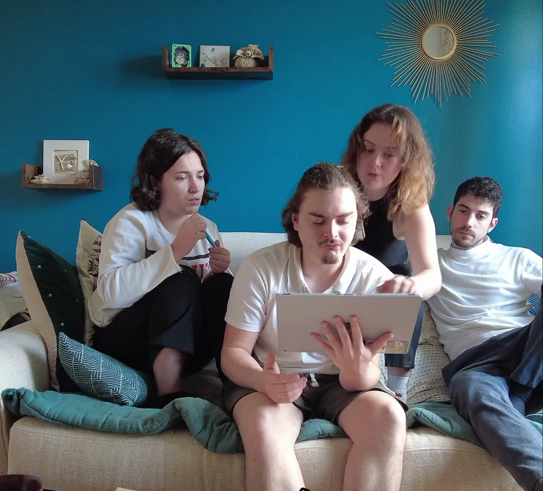 Four people seated on a couch, with one using a tablet device.