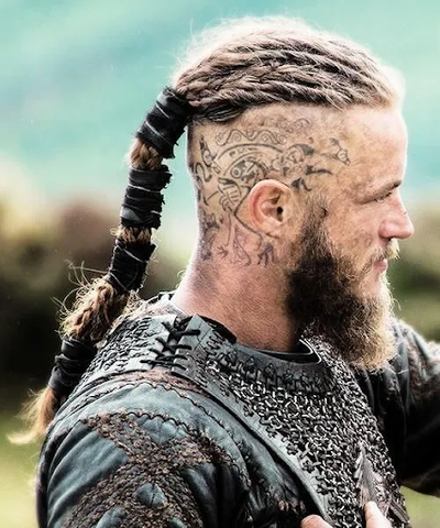 Side view of Vikings character - Ragnor, showing a mohawk and tribal tattoos on his head. 
