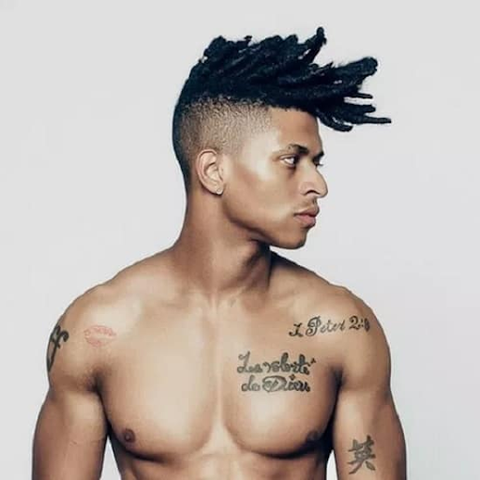 Young shirtless man with a short mohawk with dreadlocks.  