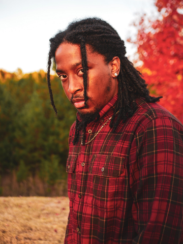 A model with long dreadlocks posing outdoors.