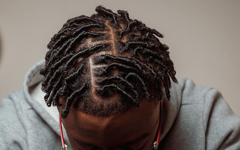 Up close view of the short twisted dreadlocks on the head of a black man.